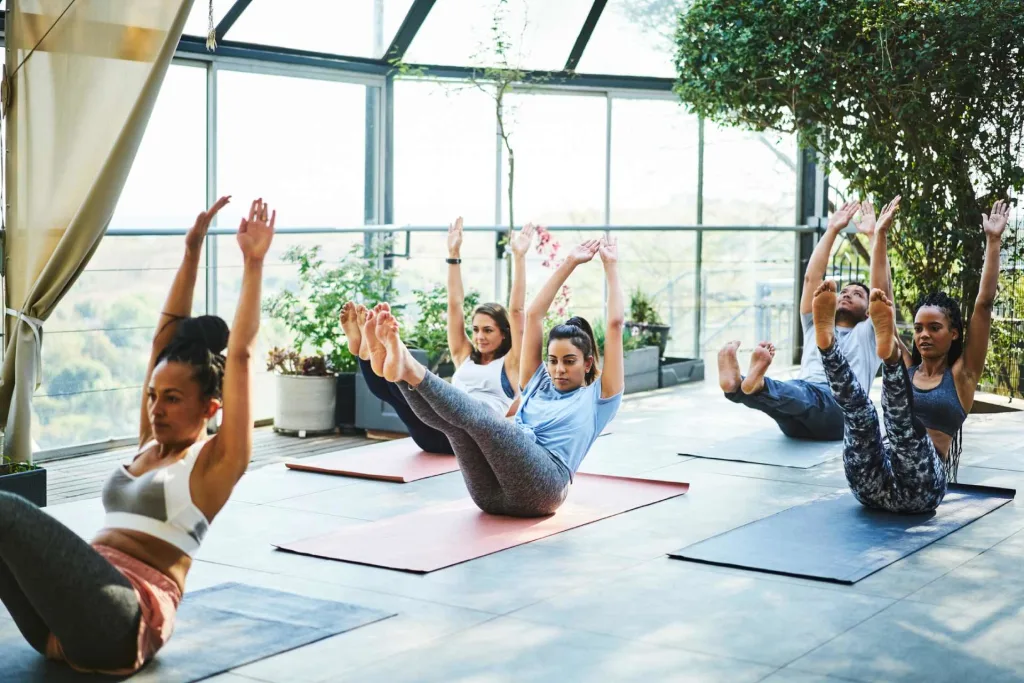 class of female yoga students practicing boat pose
